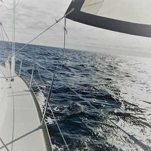 Open ocean with a part of a boat's deck and sail framing the horizon